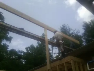 Carpenter setting a ridge beam over a new addition frame — Ice Dam Removal by Roofing Brothers in Wingina