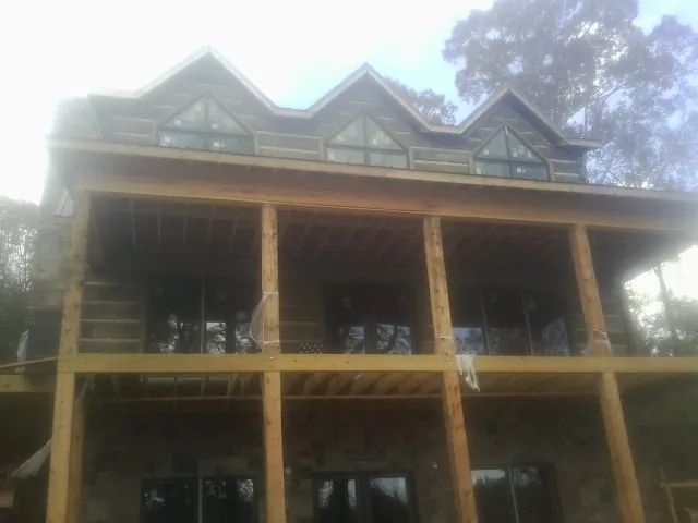 Dormers and porch framing on a large log home under construction — Roof Coating work by our crew in Wingina