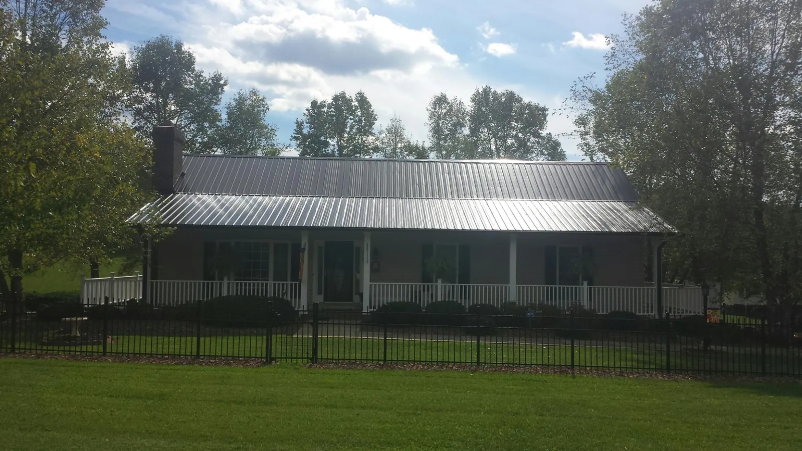 Gray metal roof on a brick ranch with a full width front porch — Gutter Guard Installation work by our crew in Wingina