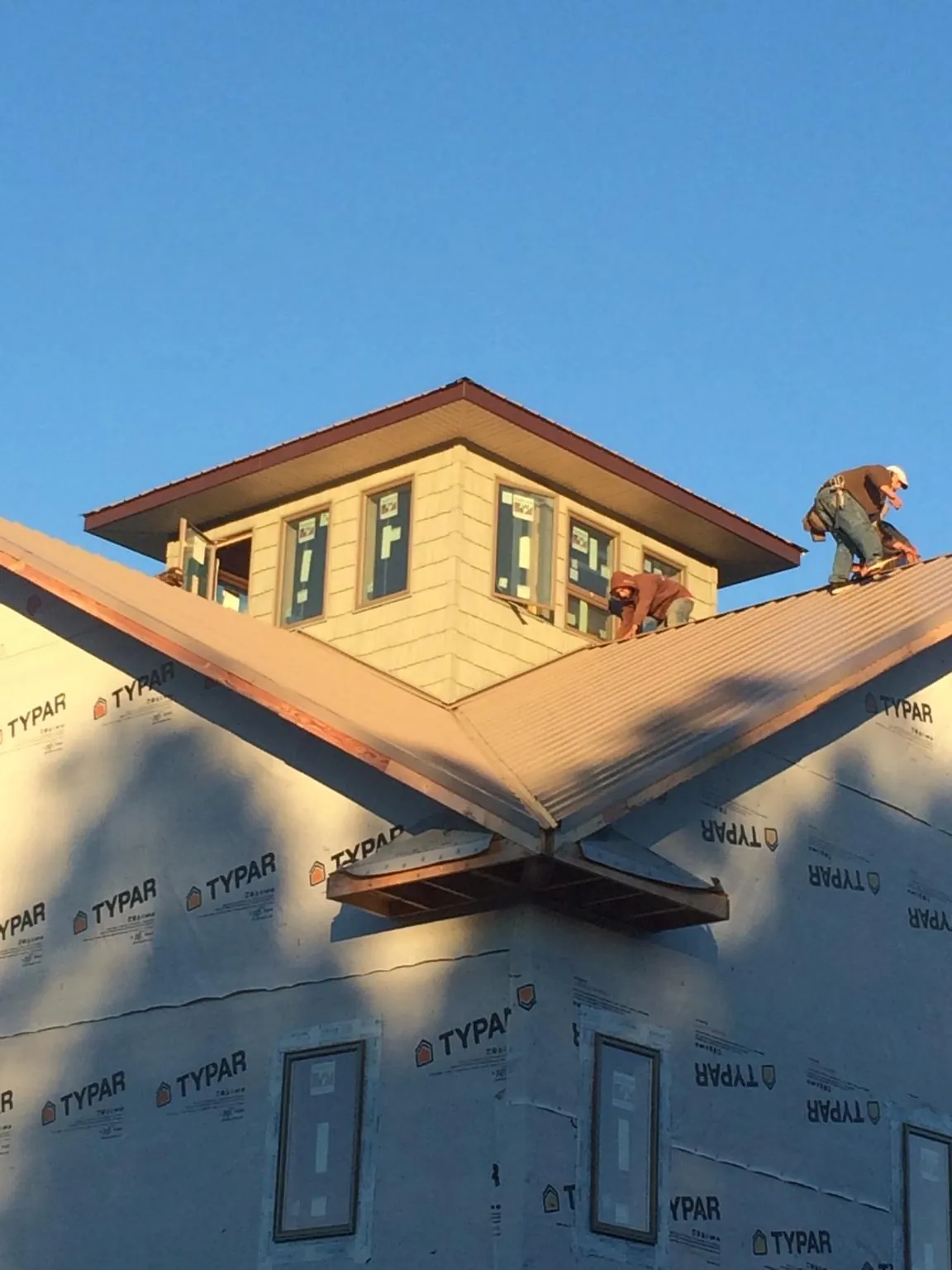 Roofers working around a rooftop cupola on a new metal roof at sunset — Roof Waterproofing in Wingina by Roofing Brothers